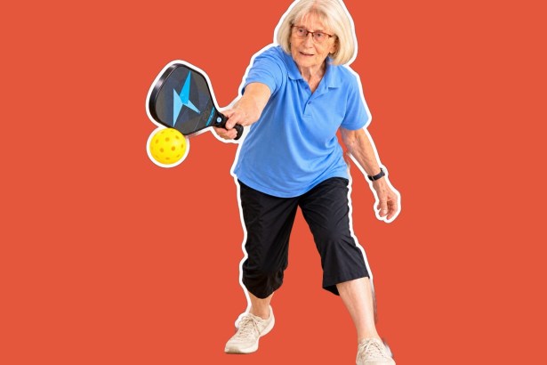 Gloria, a woman with white hair and glasses in a blue polo shirt and black cropped trousers, reaching to hit a yellow pickleball with a black and blue paddle, cut out against a coral background