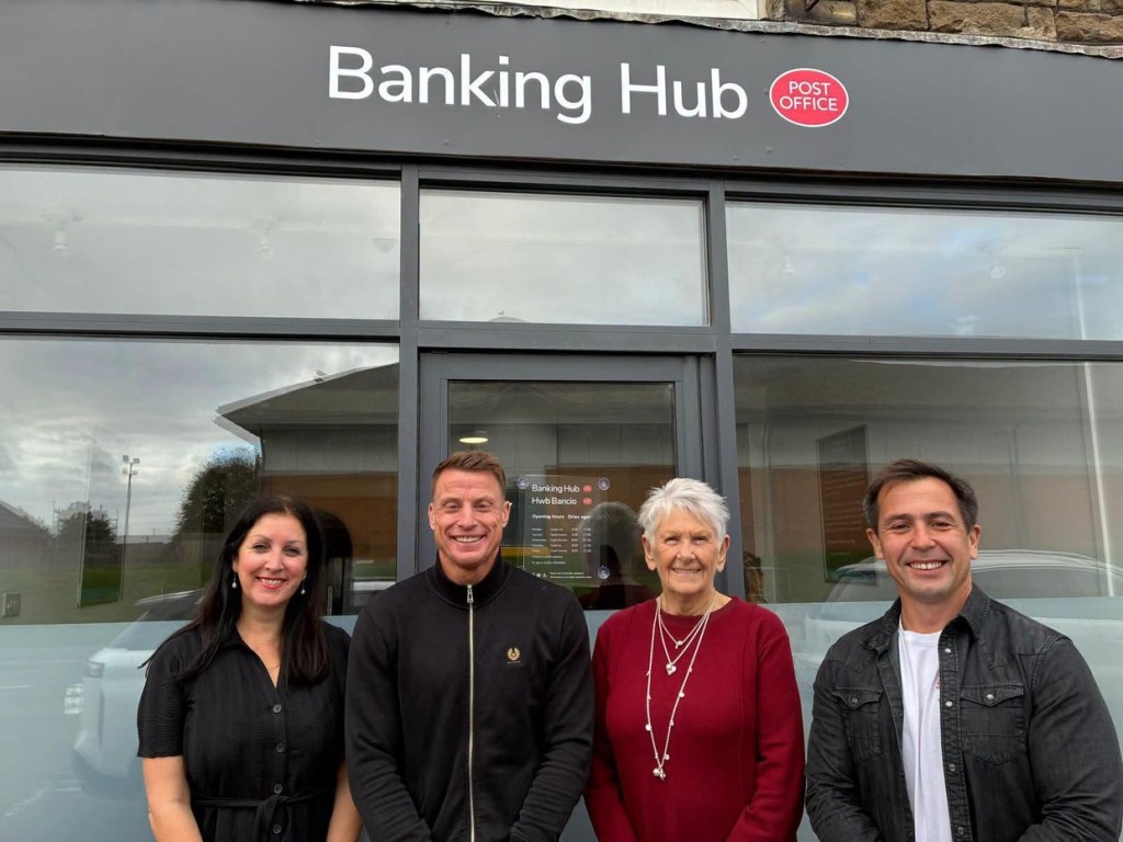 Four people standing in front of the Gorseinon Banking Hub shopfront: Cllr Nicola Matthews, Matthew Tyrell, Cllr Jan Curtice and Cllr Andrew Stevens