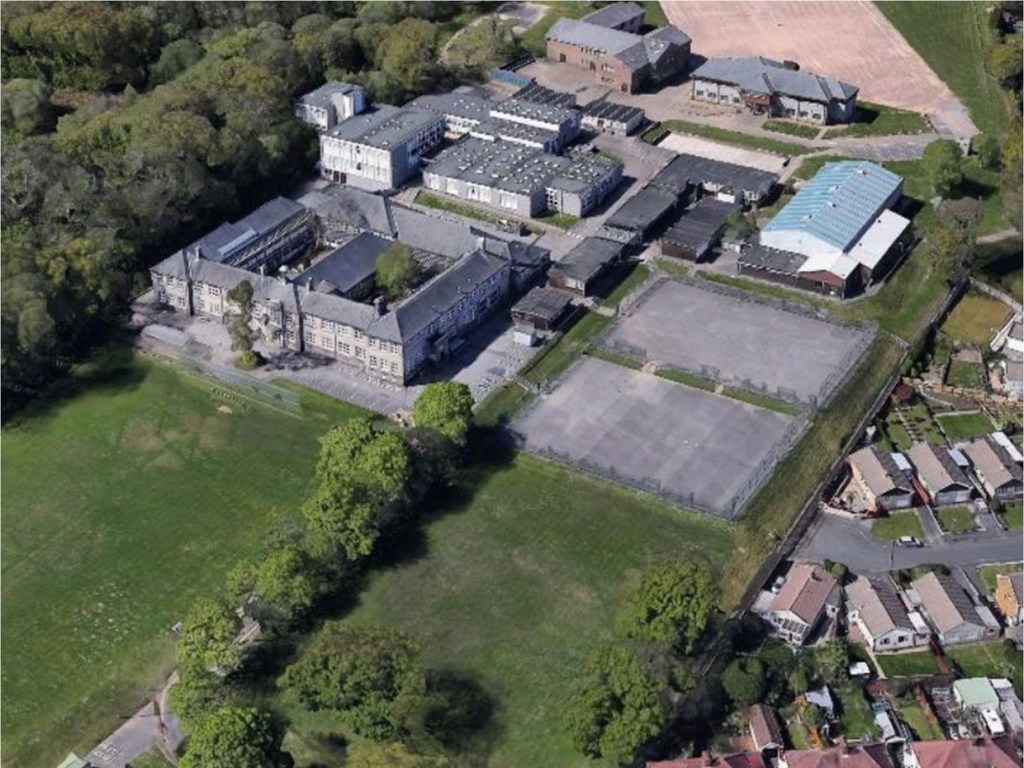 Aerial view of Gowerton School on Cecil Road, with the older stone block at the front left, flat-roofed classroom blocks behind, tennis courts and playing fields