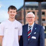 Freddie Williams, 19, in a white T-shirt beside his grandfather Handel Williams, 83, in a checked suit and striped tie, outside the engineering building at Swansea University's Bay Campus