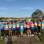A group of women runners in running kit holding yellow JogOn posters reading Run without fear of harassment