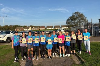 A group of women runners in running kit holding yellow JogOn posters reading Run without fear of harassment