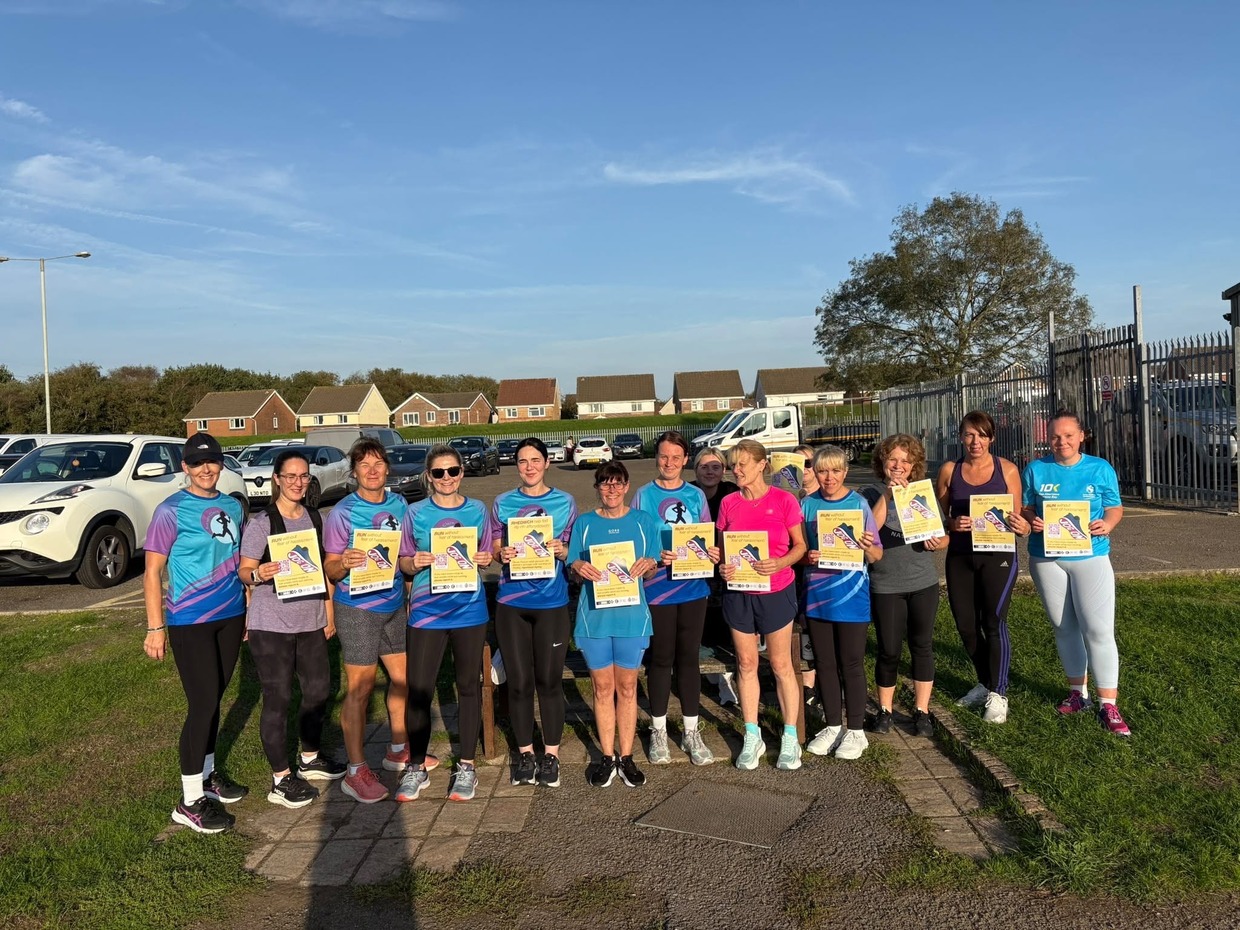 A group of women runners in running kit holding yellow JogOn posters reading Run without fear of harassment