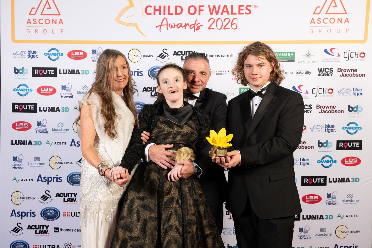 John Jenkins with his daughter Leah, son Macsen and family in evening wear in front of the Child of Wales Awards 2026 board, Macsen holding the yellow daffodil trophy