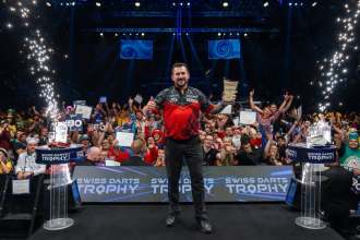 Jonny Clayton gives a thumbs up as he holds the Swiss Darts Trophy on stage in Basel in front of the crowd