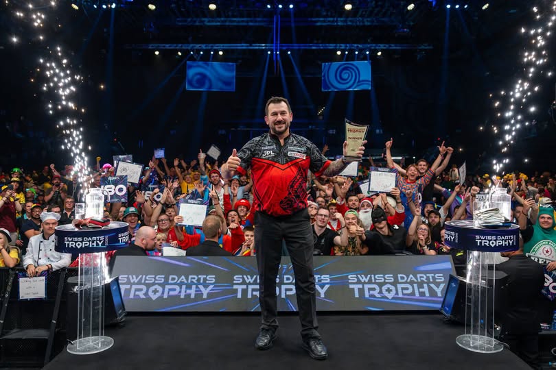 Jonny Clayton gives a thumbs up as he holds the Swiss Darts Trophy on stage in Basel in front of the crowd