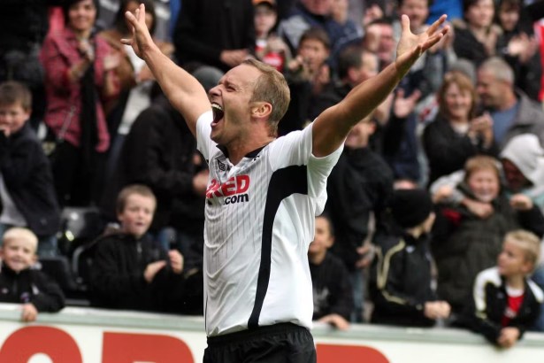 Lee Trundle in a white Swansea City shirt with both arms raised, celebrating in front of a packed stand