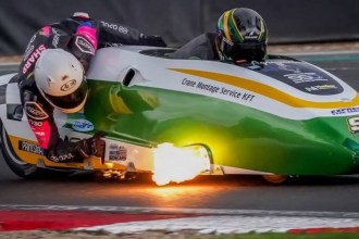 The green and white number 91 LCR Yamaha sidecar outfit leaning through a corner at Brands Hatch with flame from the exhaust, Luke Williams driving and Alfie Smith as passenger