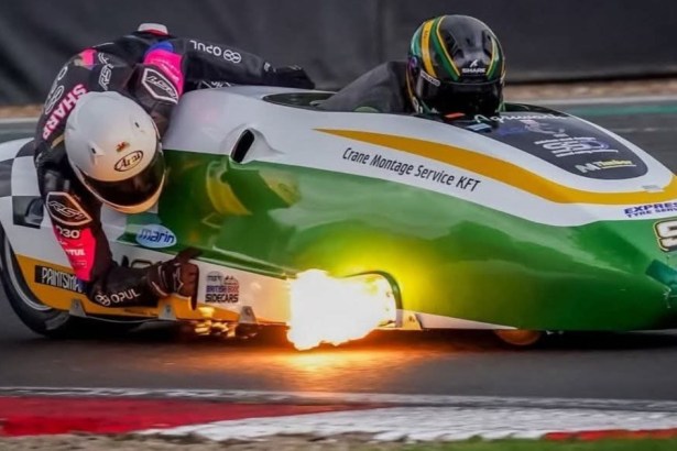 The green and white number 91 LCR Yamaha sidecar outfit leaning through a corner at Brands Hatch with flame from the exhaust, Luke Williams driving and Alfie Smith as passenger