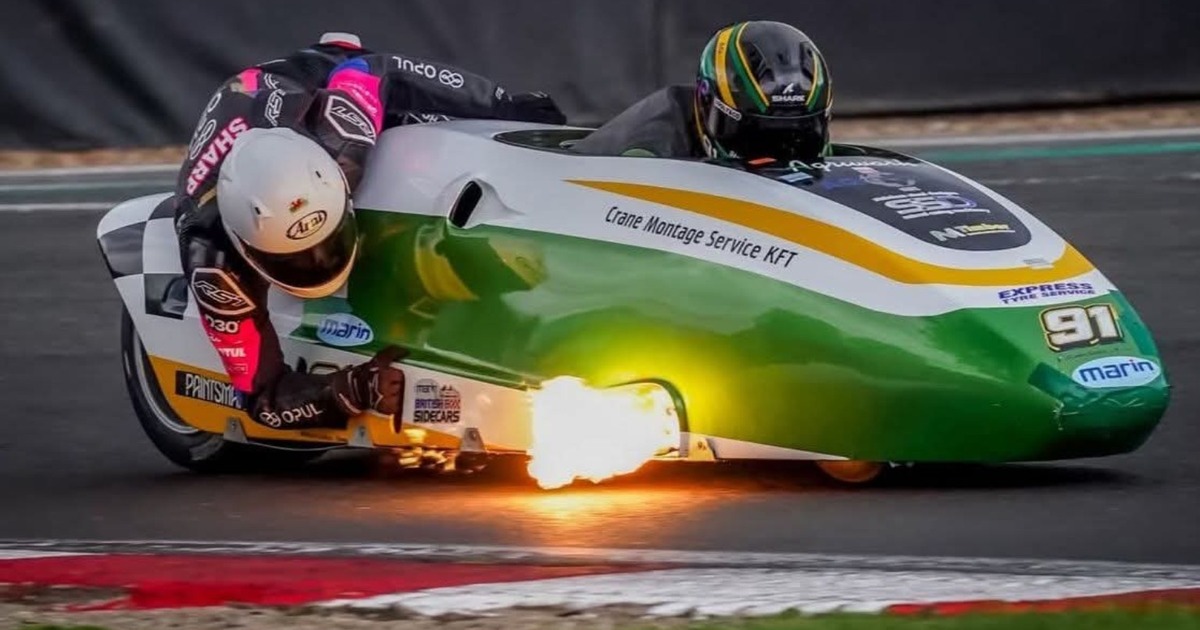 The green and white number 91 LCR Yamaha sidecar outfit leaning through a corner at Brands Hatch with flame from the exhaust, Luke Williams driving and Alfie Smith as passenger