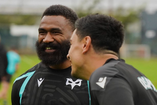 Ospreys wing Marika Koroibete, bearded and smiling, in a black Ospreys training top as a team-mate laughs beside him