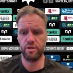 Ospreys head coach Mark Jones speaking at a press conference in front of a sponsor board