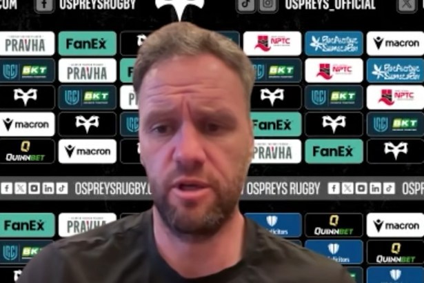 Ospreys head coach Mark Jones speaking at a press conference in front of a sponsor board