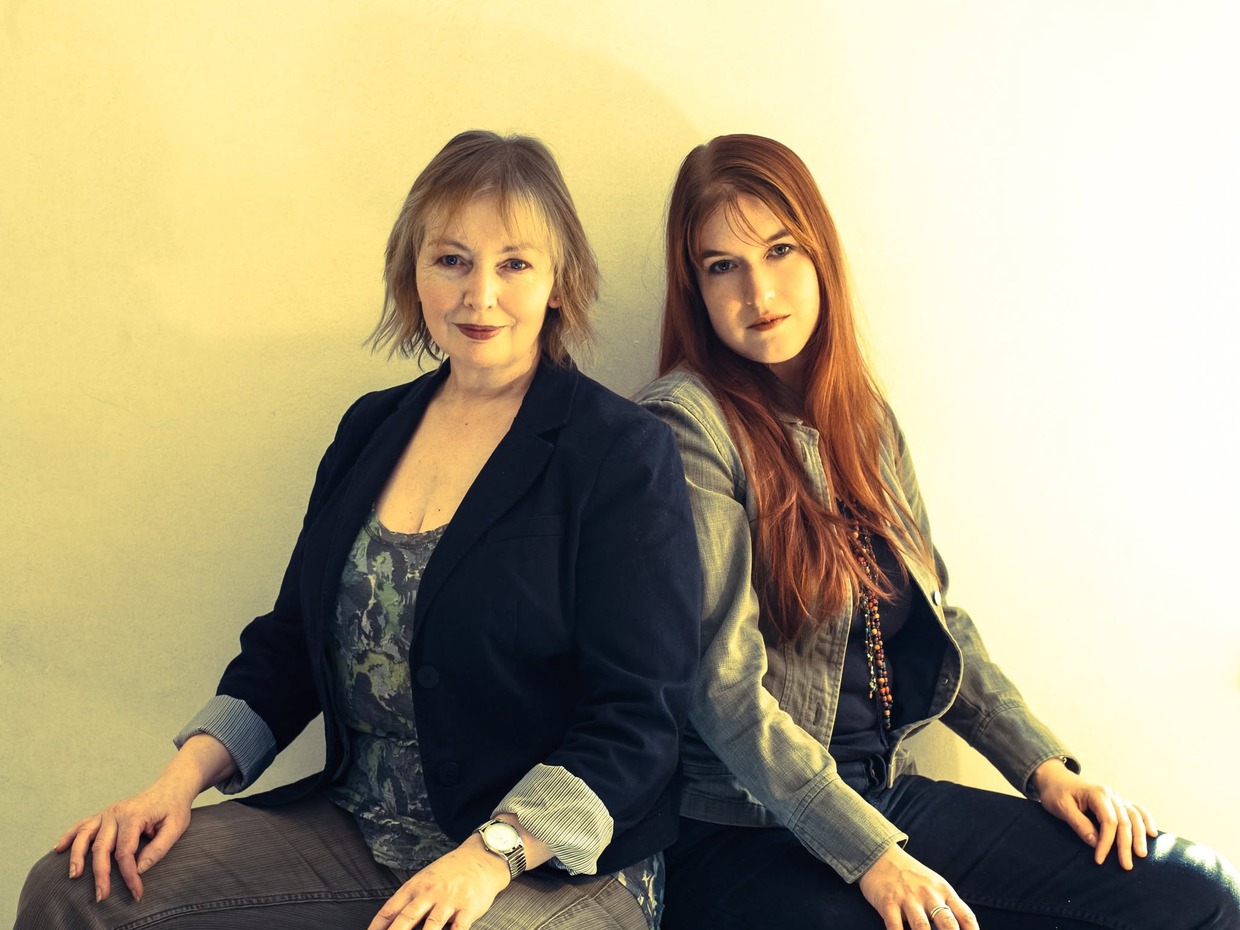Mary Hopkin and her daughter Jessica Lee Morgan sitting back to back against a plain wall