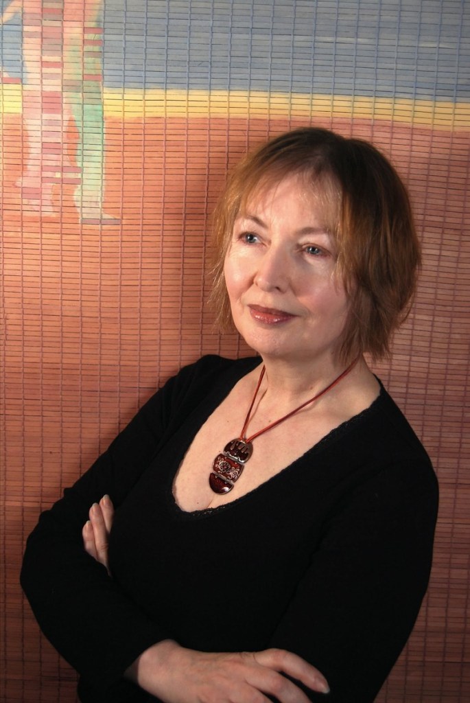 Mary Hopkin with arms folded in front of a painted blind