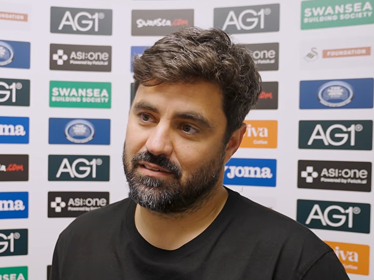 Swansea City head coach Vitor Matos speaks to the media in front of a sponsor board