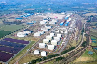 Aerial view of the Impala fuel terminal at Milford Haven, with rows of white and blue storage tanks, rail sidings and lagoons surrounded by Pembrokeshire farmland