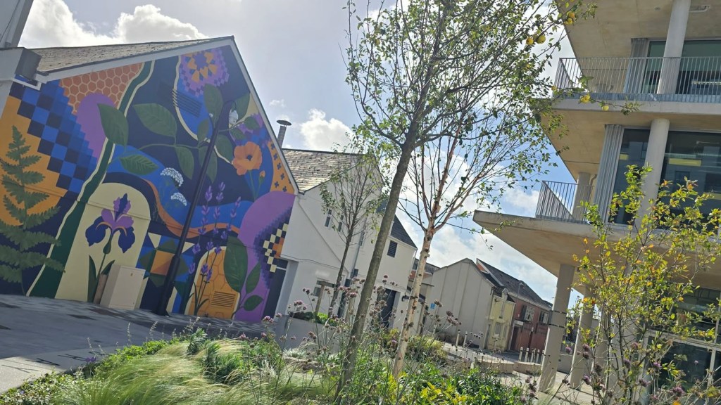 Colourful mural of ferns, lavender, irises and honeycomb on a gable wall at Mowbray Yard, Swansea