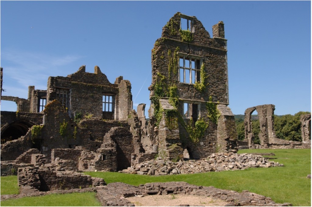 The ivy-covered stone ruins of Neath Abbey under a blue sky