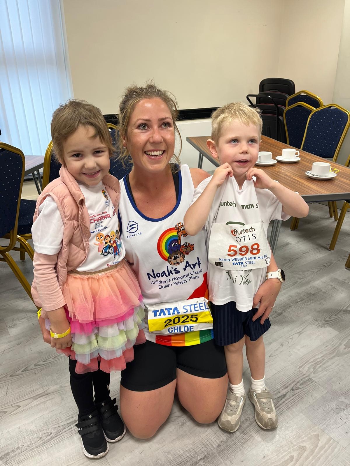 Olivia Finch in a pink gilet and tutu with a Noah's Ark Charity runner and a young Mini Miler runner