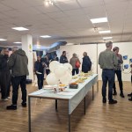 Guests chatting around a buffet table with white balloons, one printed with 10 and Oriel Science, at the Castle Street venue