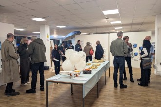 Guests chatting around a buffet table with white balloons, one printed with 10 and Oriel Science, at the Castle Street venue