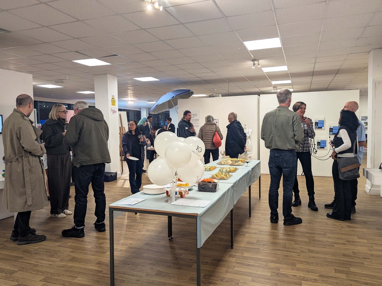 Guests chatting around a buffet table with white balloons, one printed with 10 and Oriel Science, at the Castle Street venue