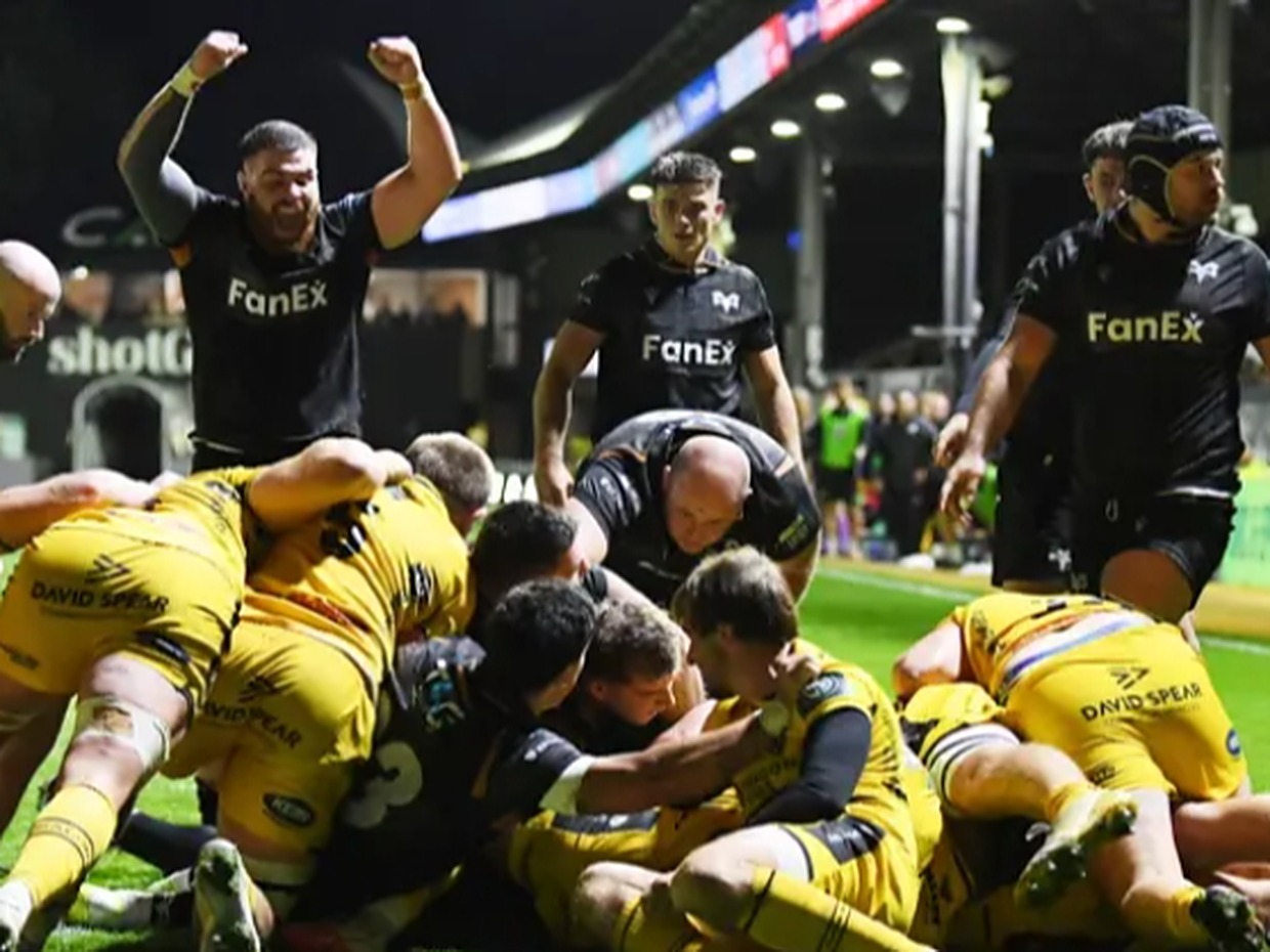 Ospreys players celebrate as a maul goes over the Dragons' line at Rodney Parade