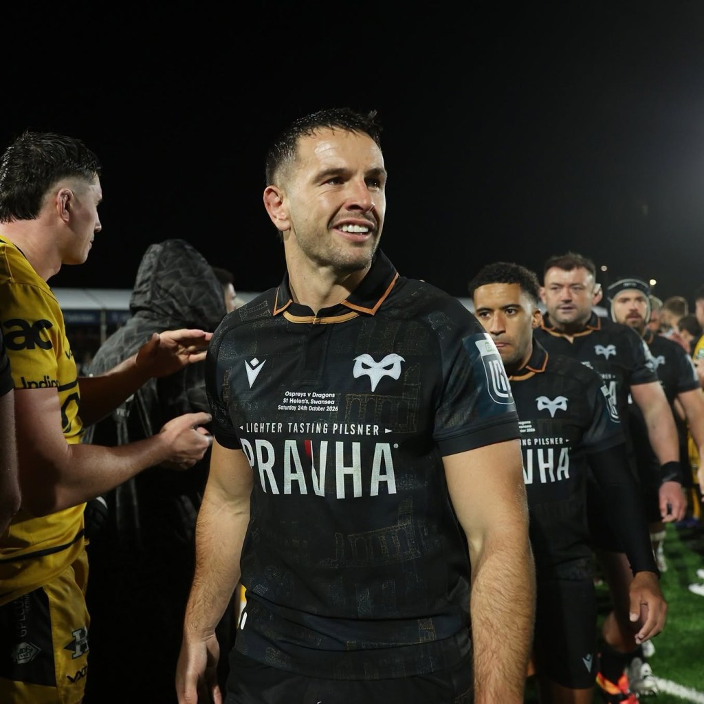An Ospreys player smiling as he walks off past the Dragons players in yellow at full-time