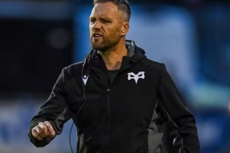 Ospreys head coach Mark Jones on the pitch in a black Ospreys jacket