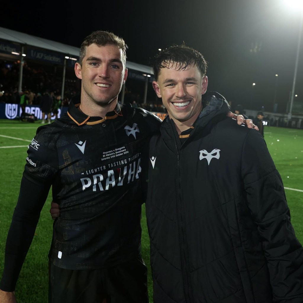 Two Ospreys players smiling with their arms round each other, one in a padded club jacket