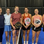 Six women players line up at the net on a blue court at Jaxx Padel in Llansamlet during the UK Padel Masters Series