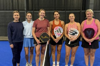 Six women players line up at the net on a blue court at Jaxx Padel in Llansamlet during the UK Padel Masters Series