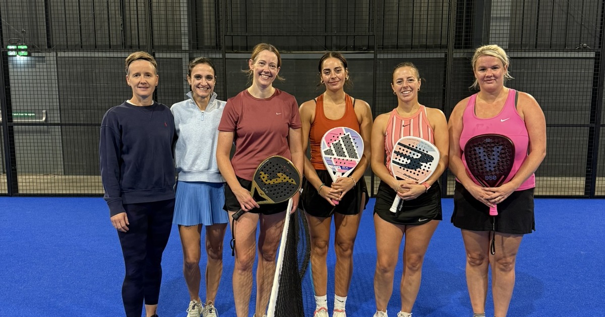 Six women players line up at the net on a blue court at Jaxx Padel in Llansamlet during the UK Padel Masters Series