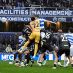 QPR defender Jimmy Dunne heads the ball over Swansea City goalkeeper Lawrence Vigouroux in a crowded penalty area at Loftus Road.