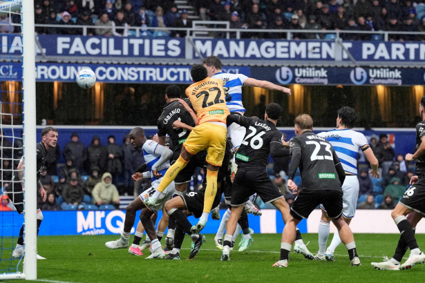QPR defender Jimmy Dunne heads the ball over Swansea City goalkeeper Lawrence Vigouroux in a crowded penalty area at Loftus Road.