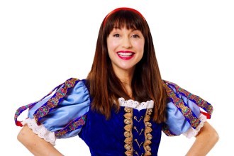 Rebecca Keatley smiling with her hands on her hips in a Snow White costume with a red headband, blue velvet bodice and puffed blue sleeves