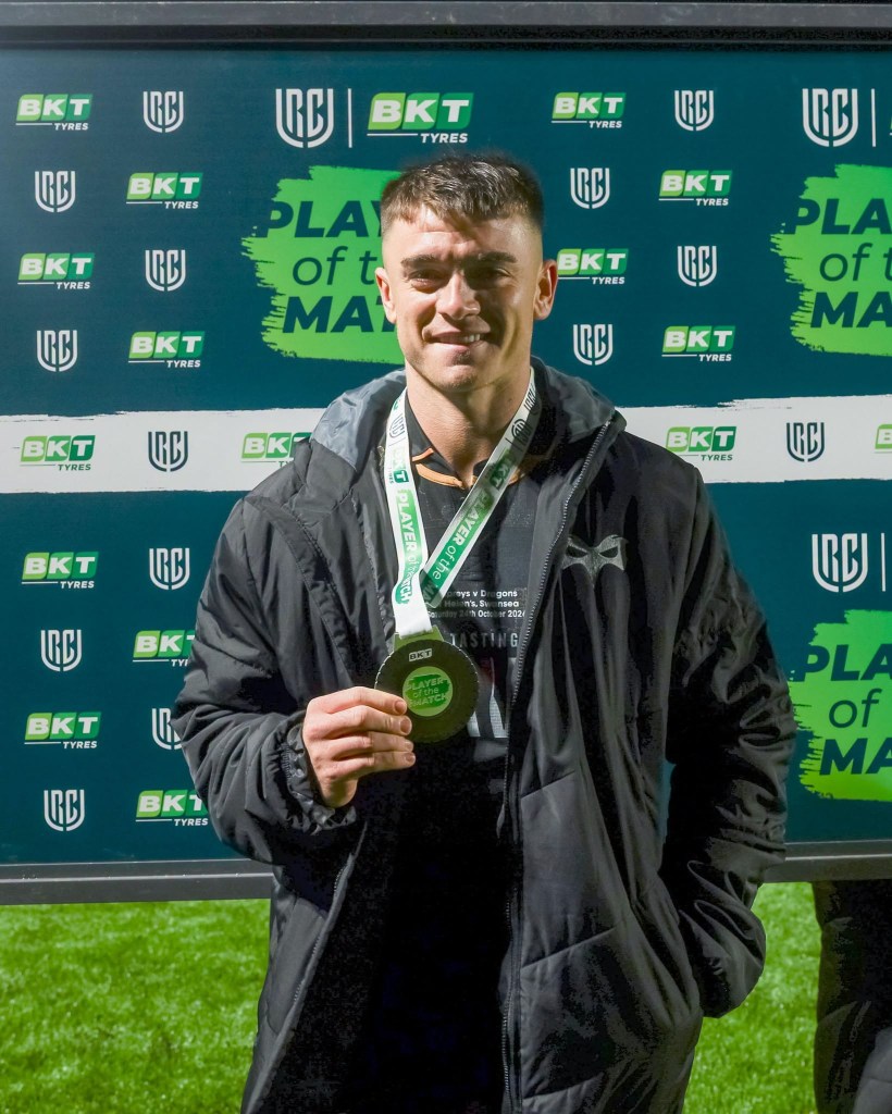 Reuben Morgan-Williams in an Ospreys jacket holding up his player of the match medal