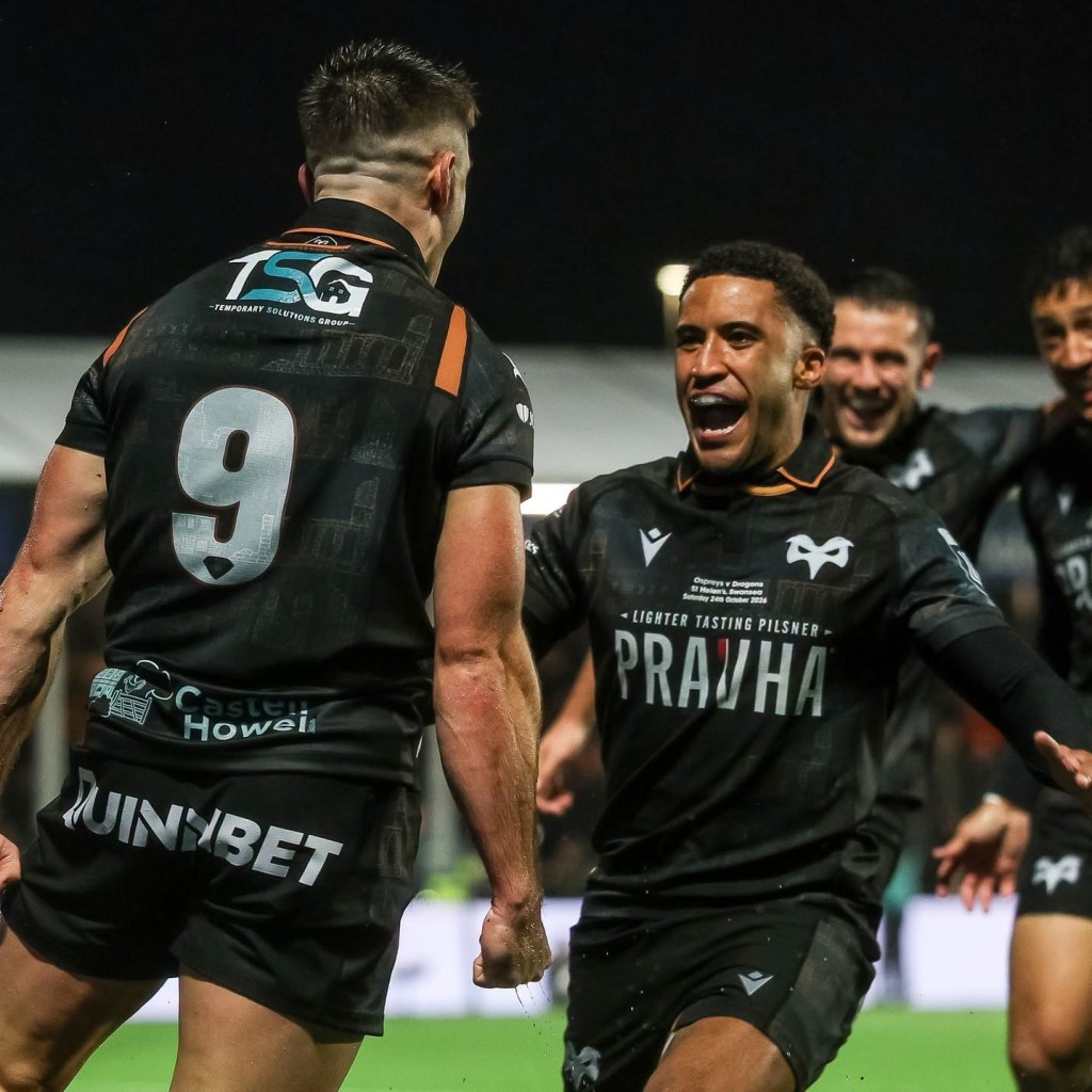Ospreys scrum-half Reuben Morgan-Williams, number 9, celebrating a try with a team-mate running towards him