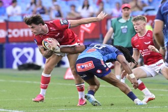 Scarlets centre Joe Roberts holds off a Bulls tackler as he carries the ball at Loftus Versfeld