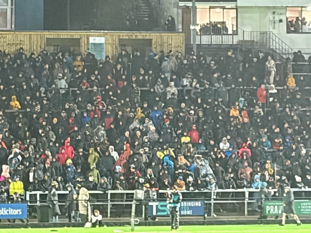 Rows of fans in hoods and rain jackets packed into the stand at St Helen’s during Storm Boelo