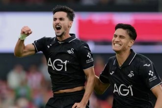 Swansea City midfielder Stephen Eustáquio, in the black away kit, shouting and clenching his fist in celebration as team-mate Marko Stamenic runs alongside