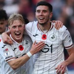 Swansea City's Stephen Welsh and Ross Stewart celebrating together in the Swans' white shirts with poppies