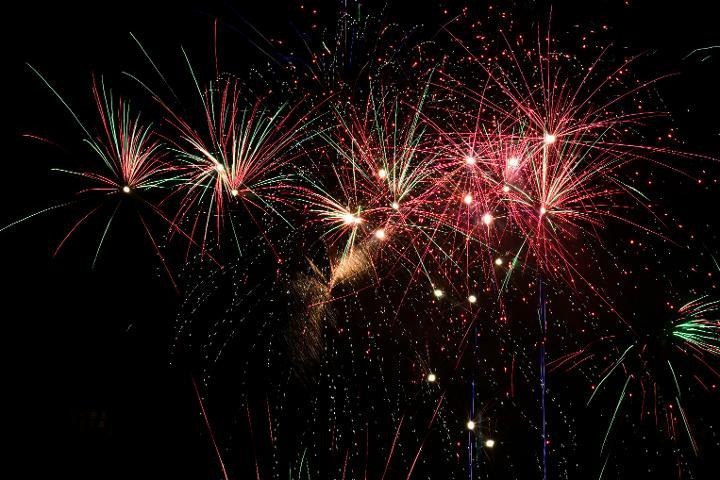 Red and green fireworks bursting against a black night sky