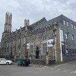 The Gothic stone building of Swansea Mosque and Islamic Community Centre with its tall pinnacled tower and a modern grey extension