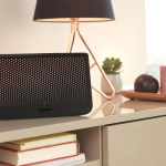 A black TalkTalk broadband router on a living room sideboard beside a television and a table lamp