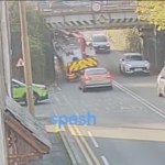 A lorry with a red crane arm under the Trafle Mill railway bridge on Victoria Road, Gowerton, with traffic queuing in both directions