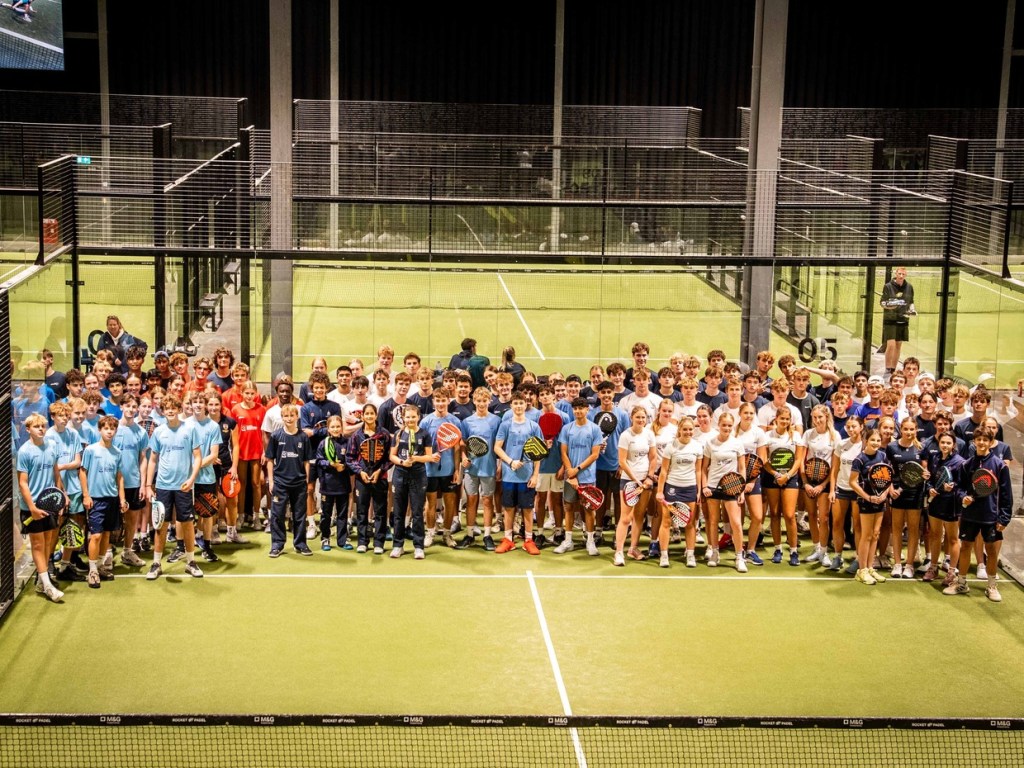 More than a hundred teenage padel players in school kit holding rackets on an indoor court at last year's UK Padel Schools Championships