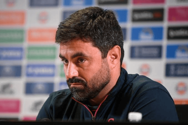 Swansea City head coach Vitor Matos at a press conference, in front of a sponsor board.