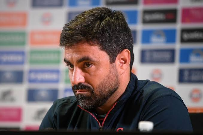 Swansea City head coach Vitor Matos at a press conference, in front of a sponsor board.